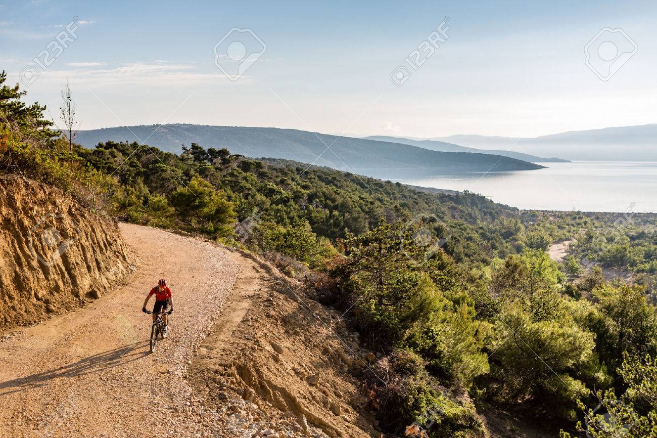 Mountain biker riding on bike in autumn inspirational mountains landscape. Man cycling biking on dirt road, trail track. Sport fitness motivation and inspiration outdoors MTB rider training, Croatia. - 61812328 Mountain biker riding on bike in autumn inspirational mountains landscape. Man cycling biking on dirt road, trail track. Sport fitness motivation and inspiration outdoors MTB rider training, Croatia. - 61812328