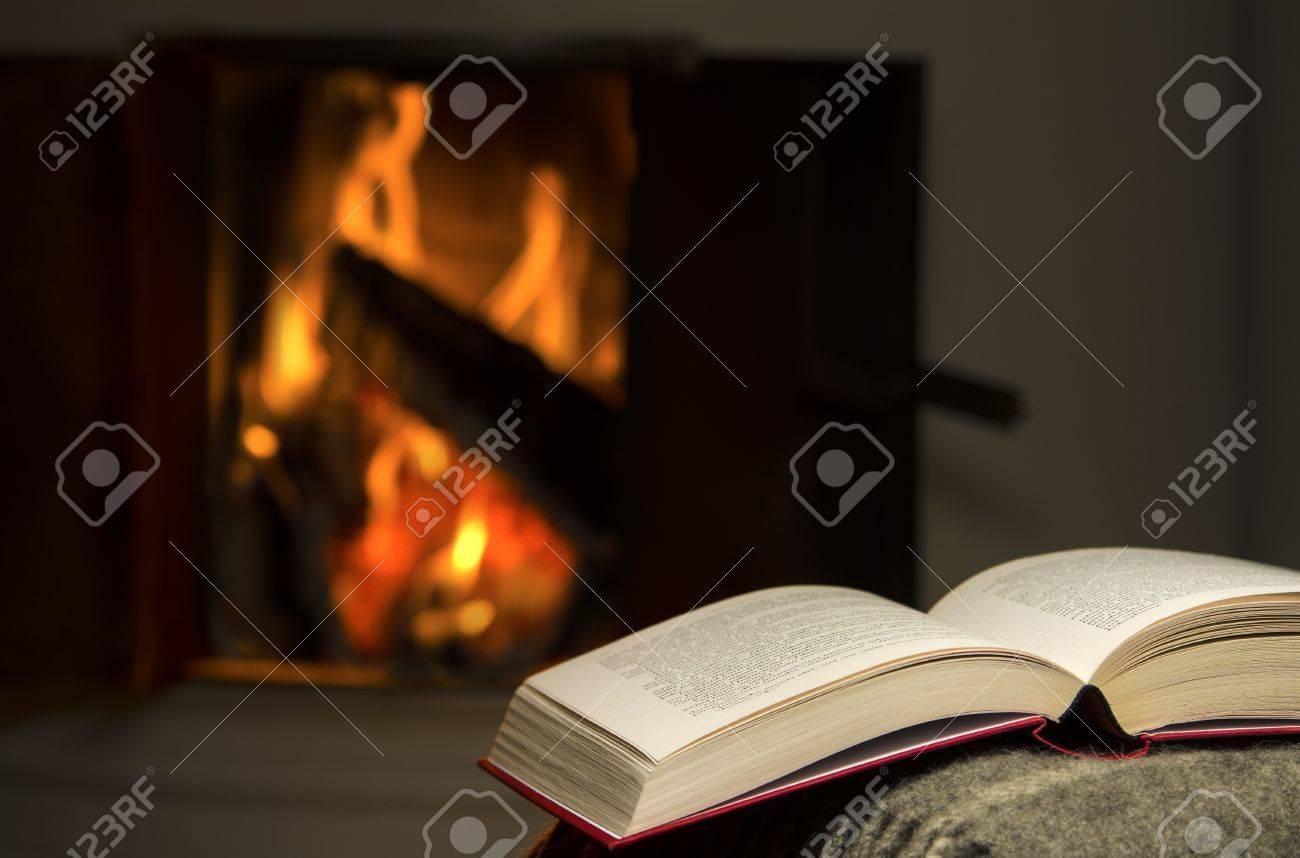 開いた本の背景にソファの暖かい暖炉の腕の残りで休んでの穏やかで温かいイメージ の写真素材 画像素材 Image 1743