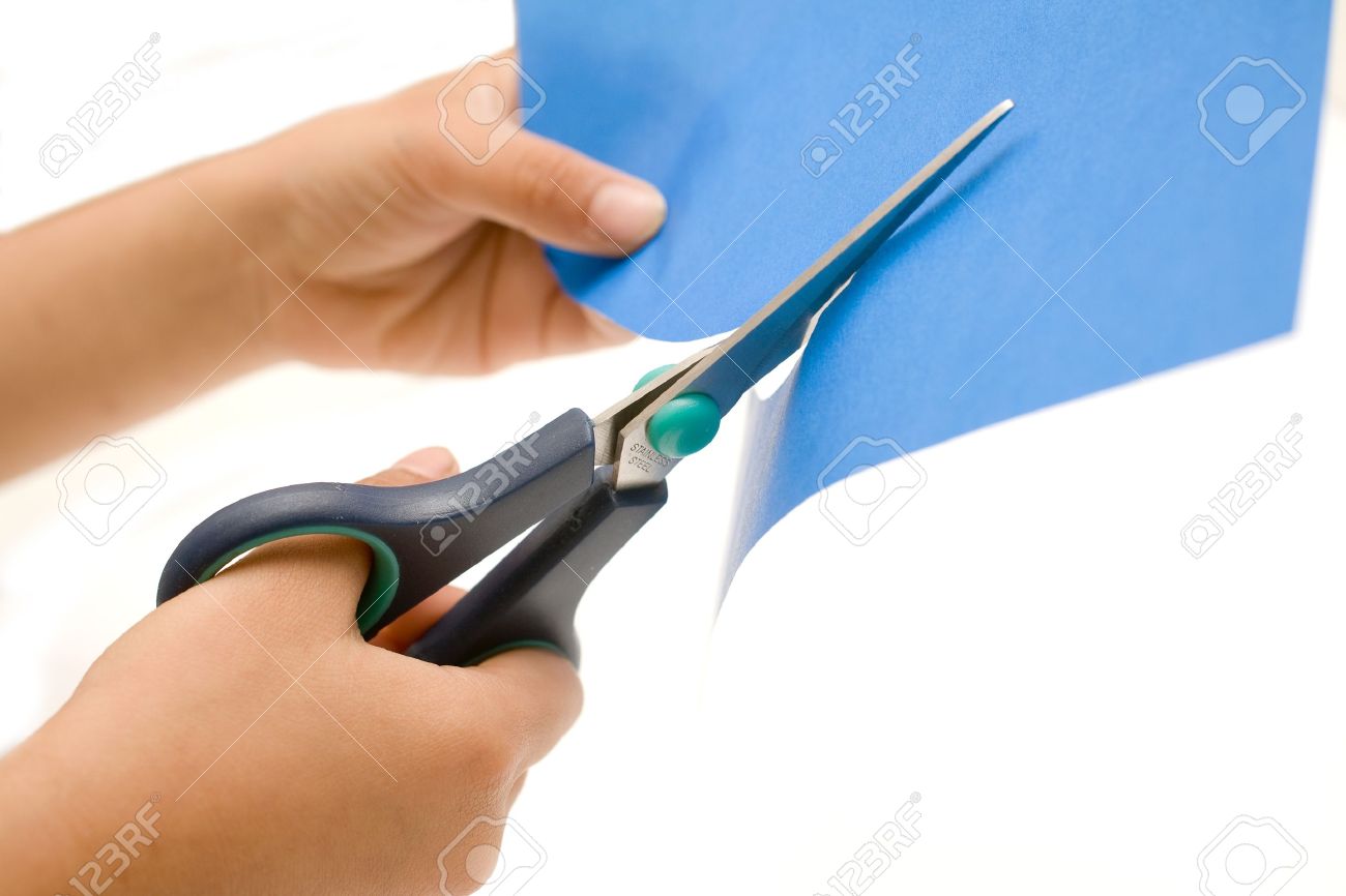 白で青い紙のシートを切る世帯のはさみのペアを保持している手 の写真素材 画像素材 Image