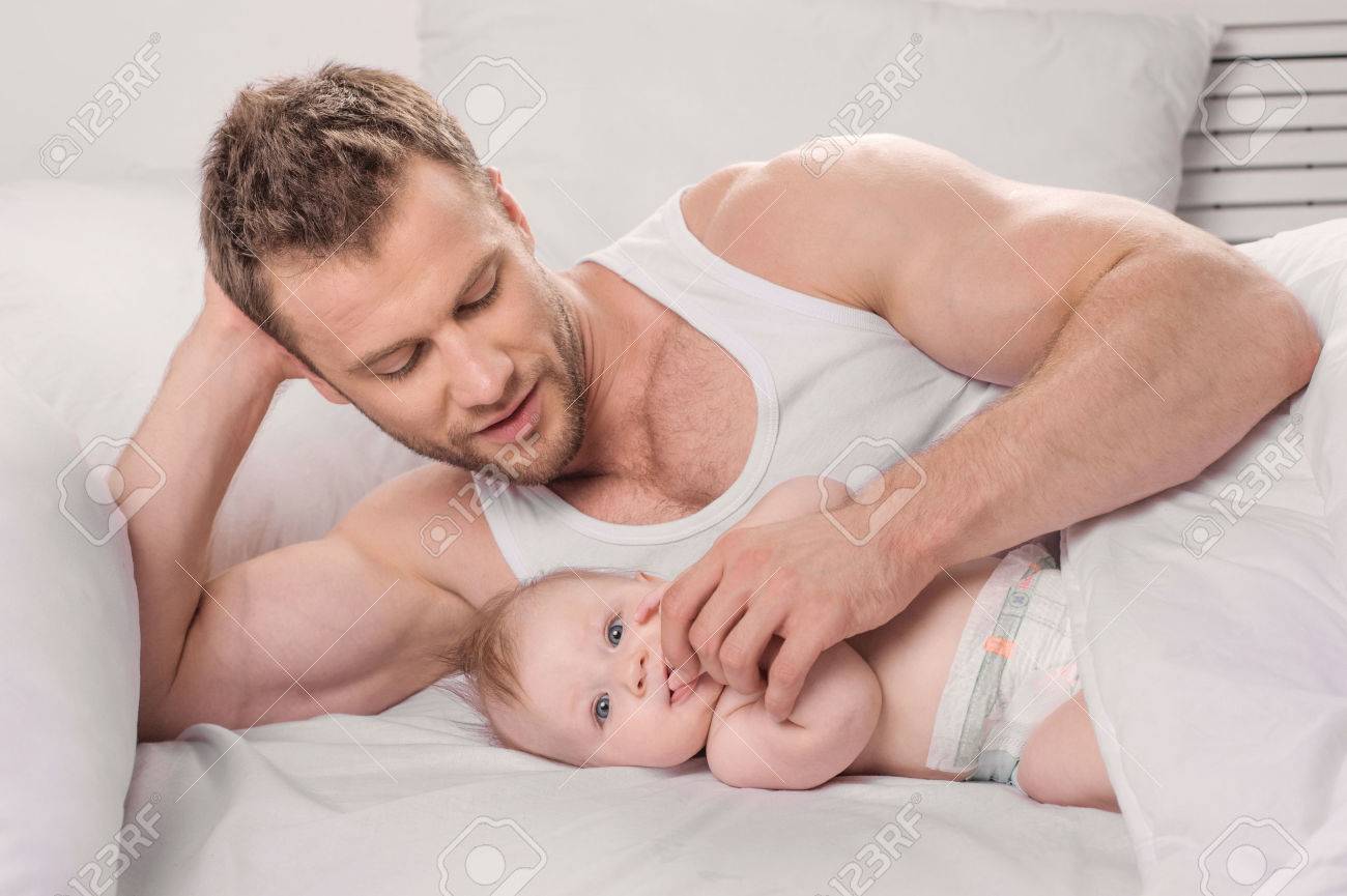 Man With Little Baby Young Muscular Man And Little Baby Lying On The Bed Stock Photo Picture And Royalty Free Image Image