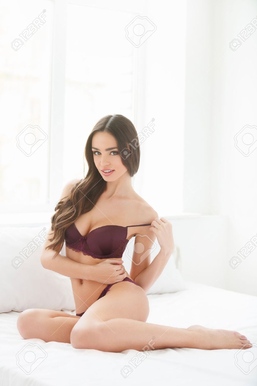 Mujeres Desnudarse. Joven Y Bella Mujer En Ropa Interior Mientras Está Sentado En El Sofá Y Mirando A La Cámara Fotos, Retratos, Imágenes Y Fotografía De Archivo Libres De Derecho. Image