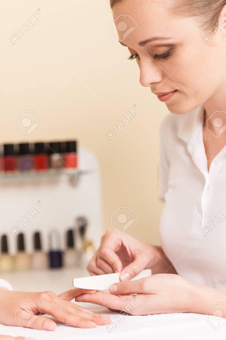 Close-up Of Beautician Hand Filing Nails Of Woman In Salon. manucurist women sitting in spa salon and looking at fingers - 33126057 Close-up Of Beautician Hand Filing Nails Of Woman In Salon. manucurist women sitting in spa salon and looking at fingers - 33126057