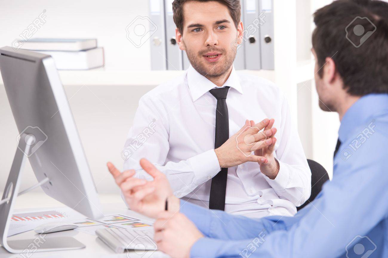 two businessmen having discussion in office. over shoulder view of businessmen looking at each other and using laptop - 33247207 two businessmen having discussion in office. over shoulder view of businessmen looking at each other and using laptop - 33247207