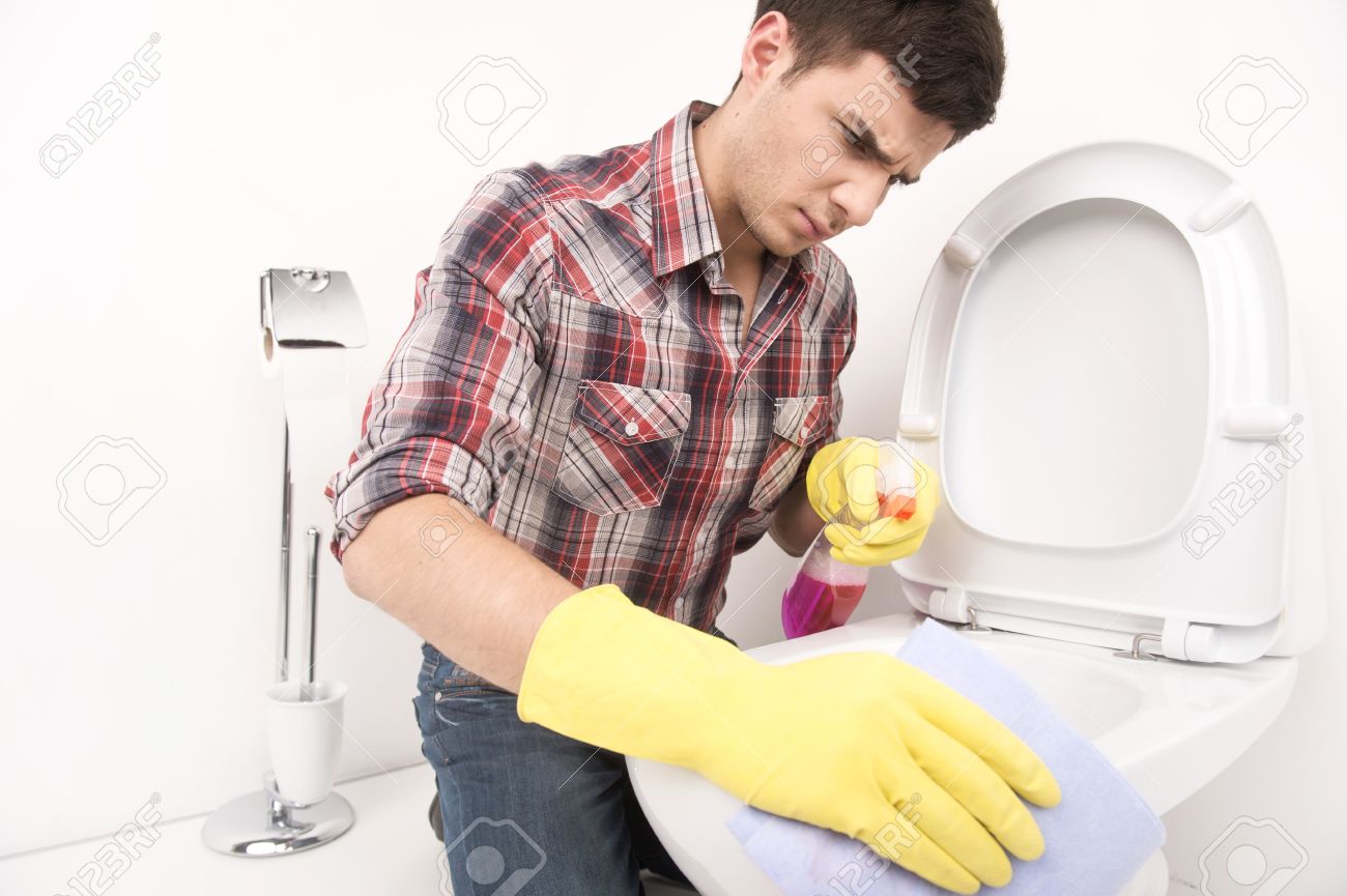man cleaning toilet with spray cleaner. disappointed guy wiping toilet seat in bathroom - 33484608 man cleaning toilet with spray cleaner. disappointed guy wiping toilet seat in bathroom - 33484608