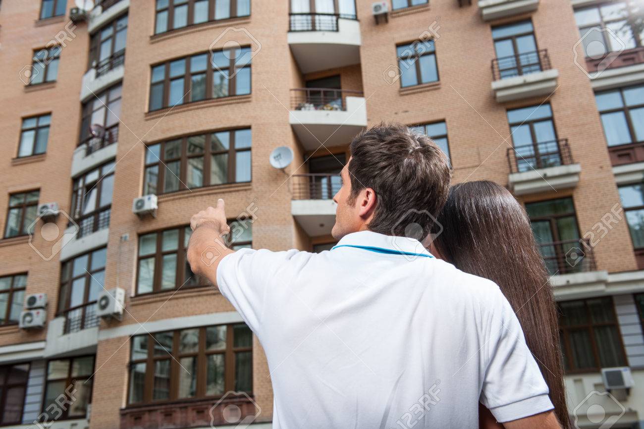 couple standing with their backs towards camera. man pointing to apartment window for brunette woman - 33933210 couple standing with their backs towards camera. man pointing to apartment window for brunette woman - 33933210