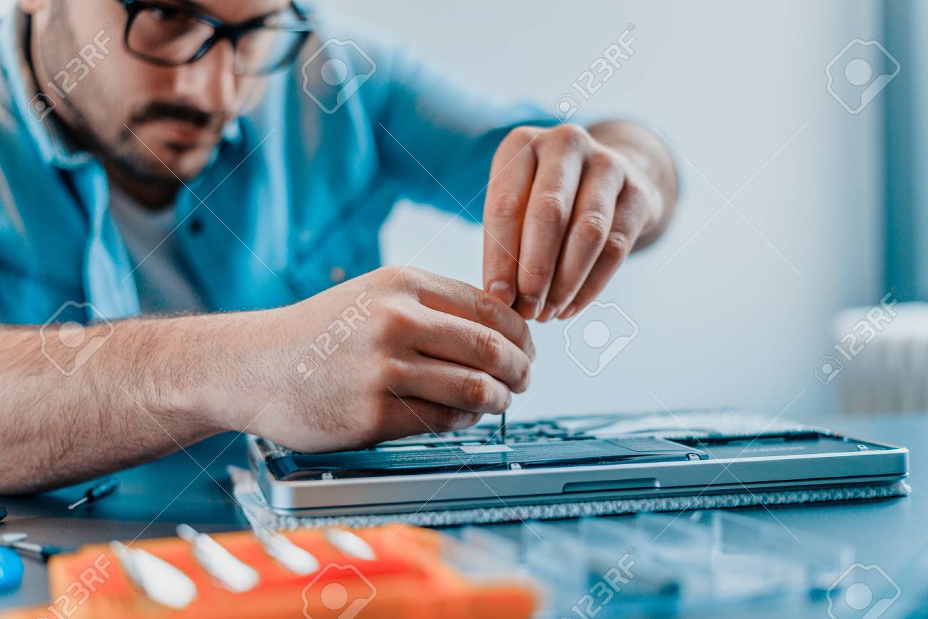 Engineer repairs laptop with screwdriver.Close-up. - 98132353 Engineer repairs laptop with screwdriver.Close-up. - 98132353