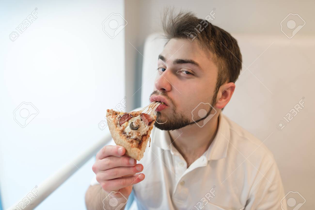 Portrait D Un Homme Qui Mange Un Morceau De Pizza Et Regarde Dans La Camera Un Homme Avec Une Barbe Apprecie Le Gout De La Pizza Chaude Banque D Images Et Photos Libres De