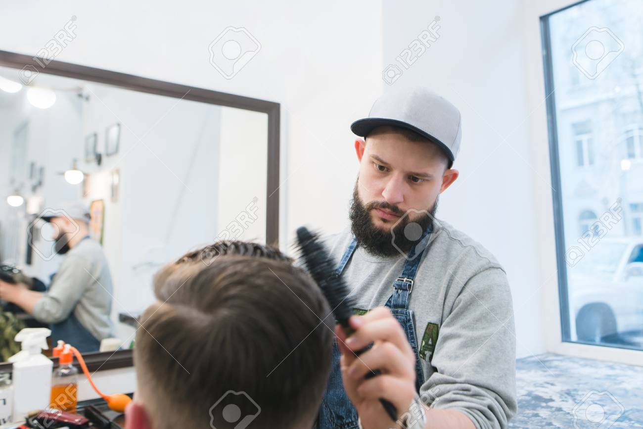 Barber With A Beard Creates A Stylish Hairstyle For A Young Man