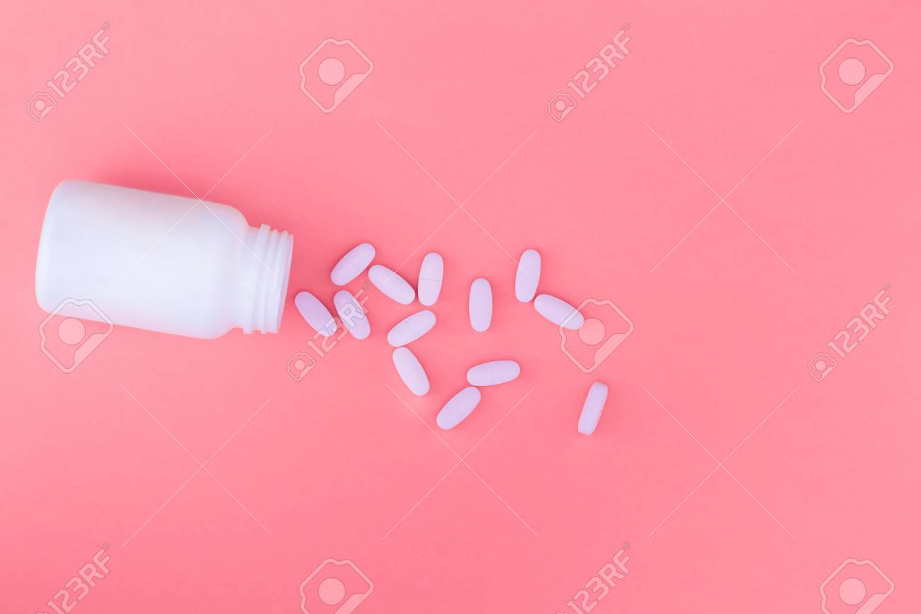 A Bottle Of Medicines And Scattered Pills On A Pastel Pink