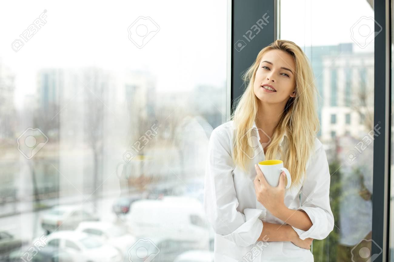 Hermosa Rubia Mujer De Pie Junto A Una Ventana, Vestido Con Hermosa Rubia Mujer De Pie Junto A Una Ventana, Vestido Con