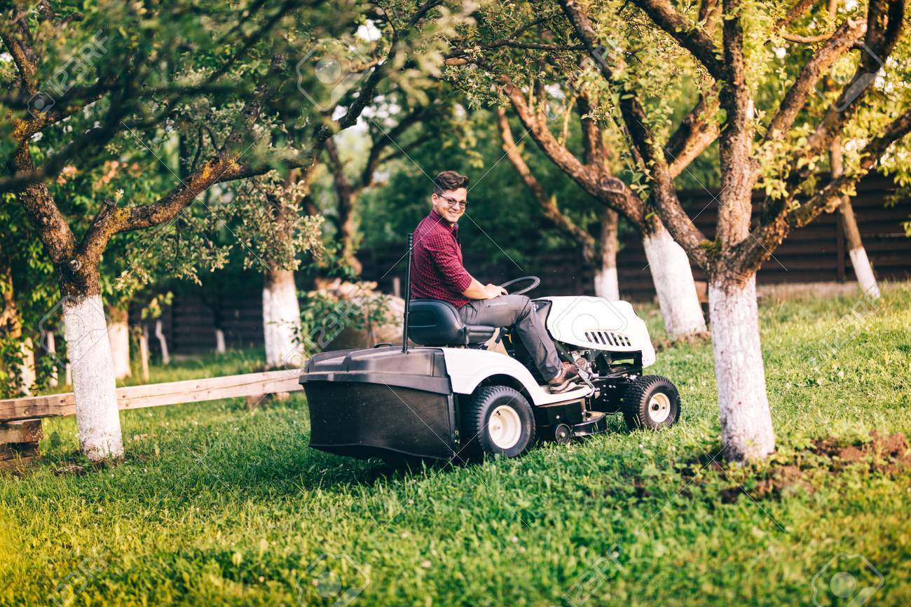 smiling gardner working and cutting grass in garden detail of works garden equipment