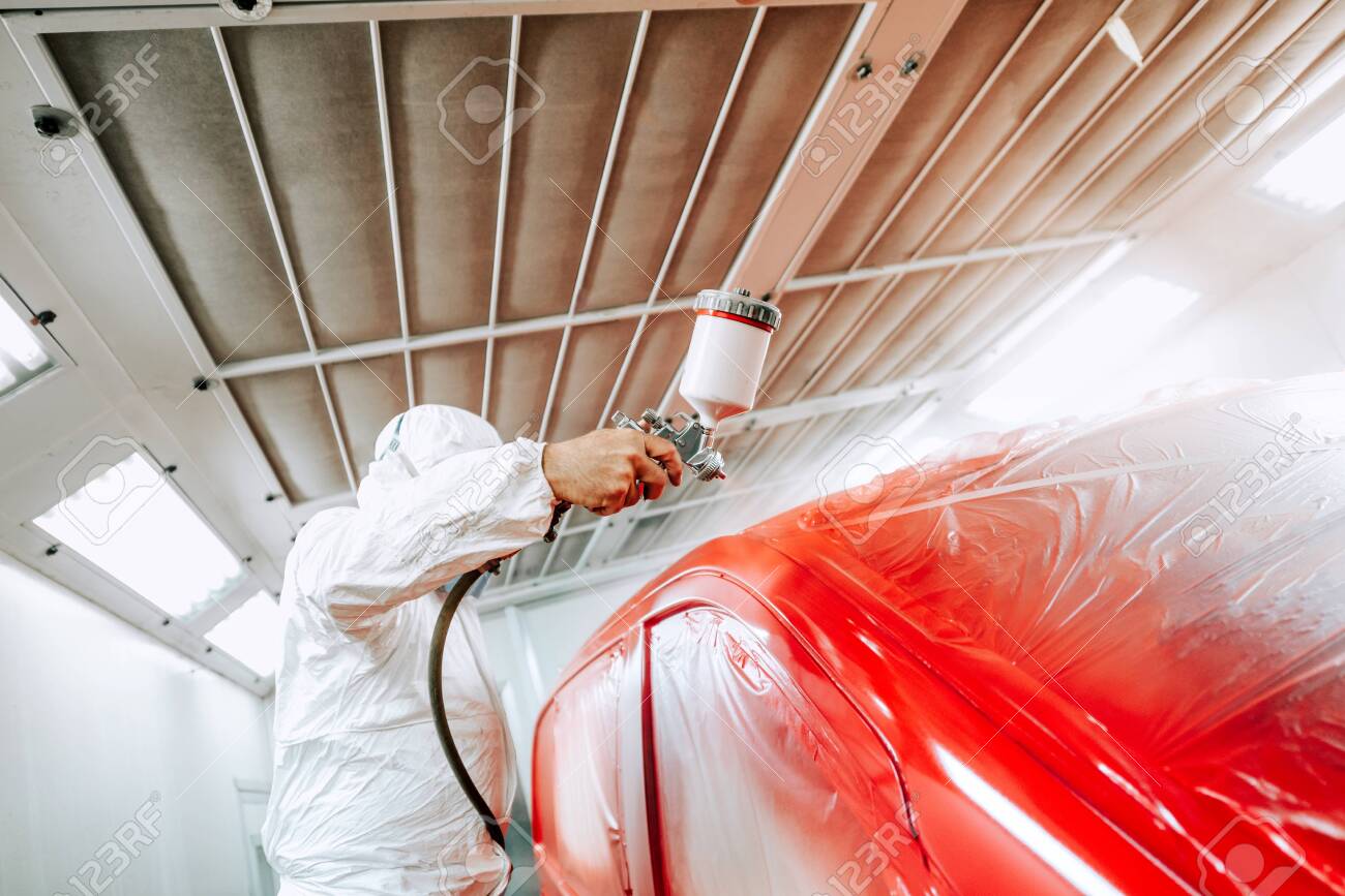 Portrait Of Man With Spray Gun With Red Paint Painting A Car
