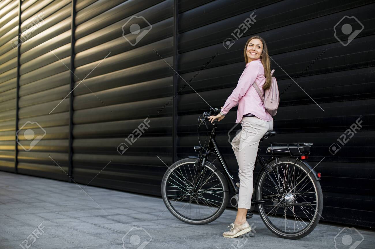 Pretty young woman with modern city electric e-bike as clean sustainable urban transportation - 134387959 Pretty young woman with modern city electric e-bike as clean sustainable urban transportation - 134387959