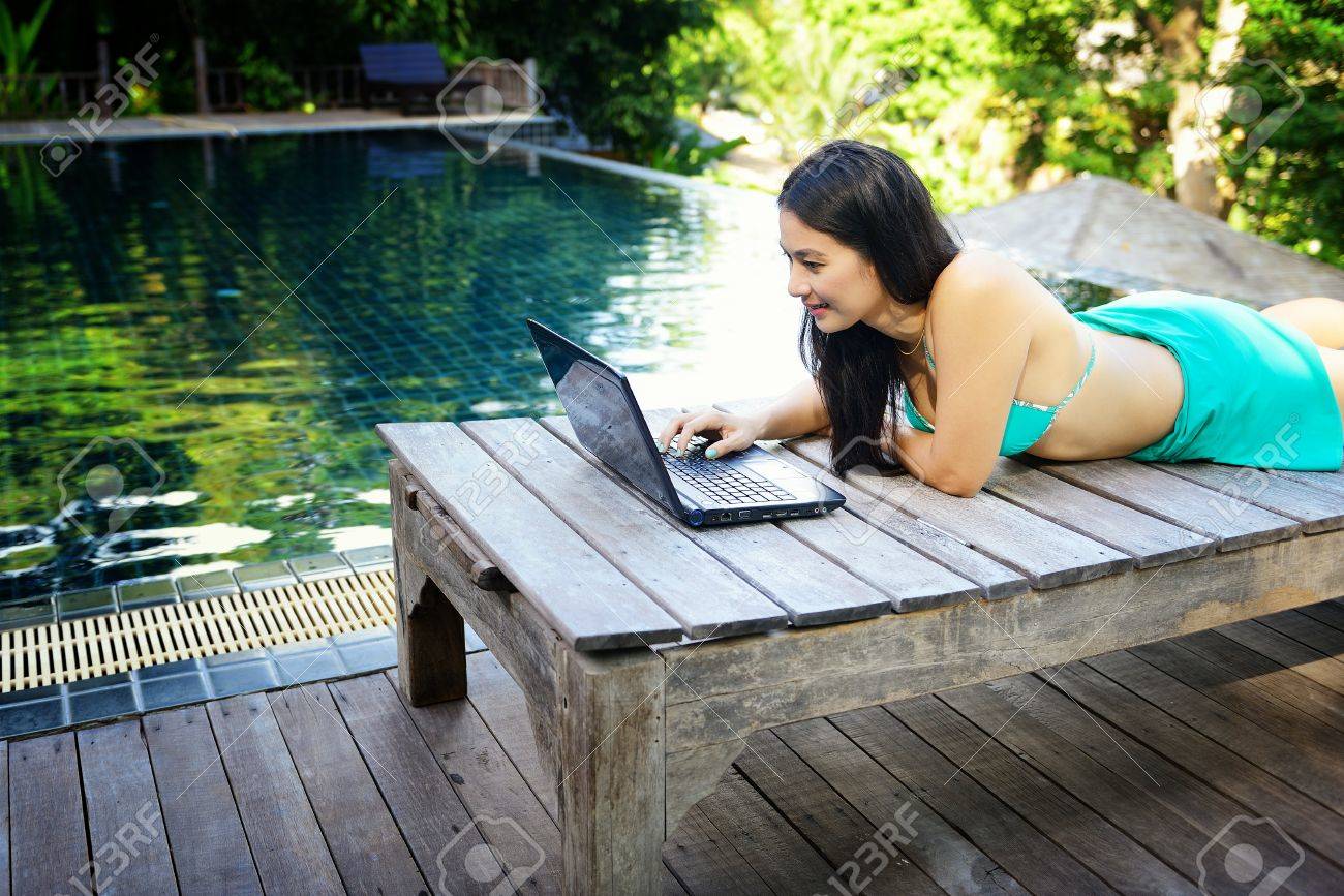 Thai beautiful woman using a laptop at the swimming pool - 22060562 Thai beautiful woman using a laptop at the swimming pool - 22060562