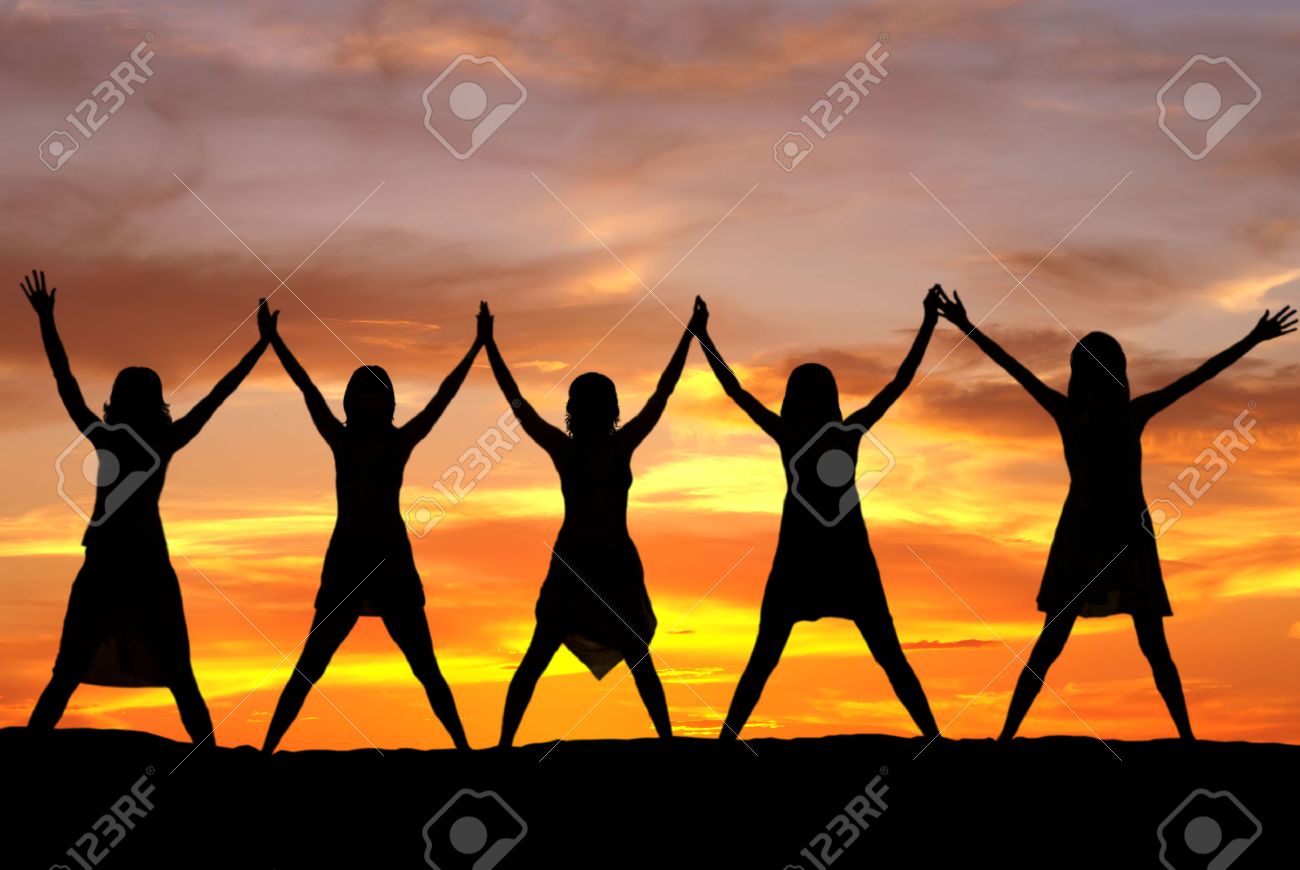 Happy celebrating women at sunset or sunrise standing elated with arms raised up above their heads - 34517527 Happy celebrating women at sunset or sunrise standing elated with arms raised up above their heads - 34517527