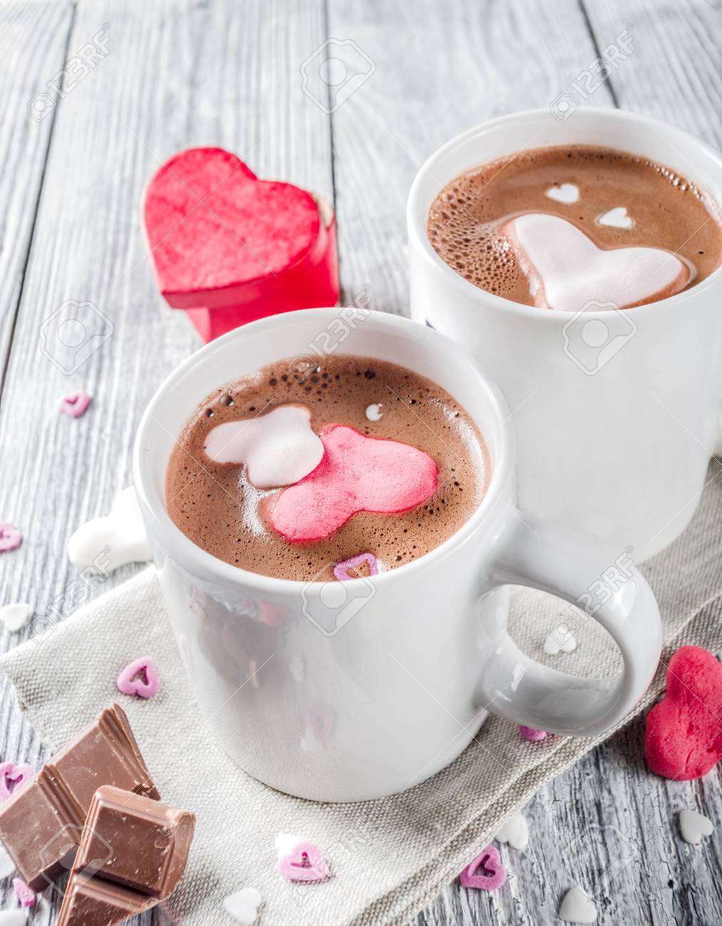 Valentines day treat ideas, two cups hot chocolate drink with marshmallow hearts red pink white color with chocolate pieces, sugar sprinkles, old wooden background copy space top view - 121713602 Valentines day treat ideas, two cups hot chocolate drink with marshmallow hearts red pink white color with chocolate pieces, sugar sprinkles, old wooden background copy space top view - 121713602