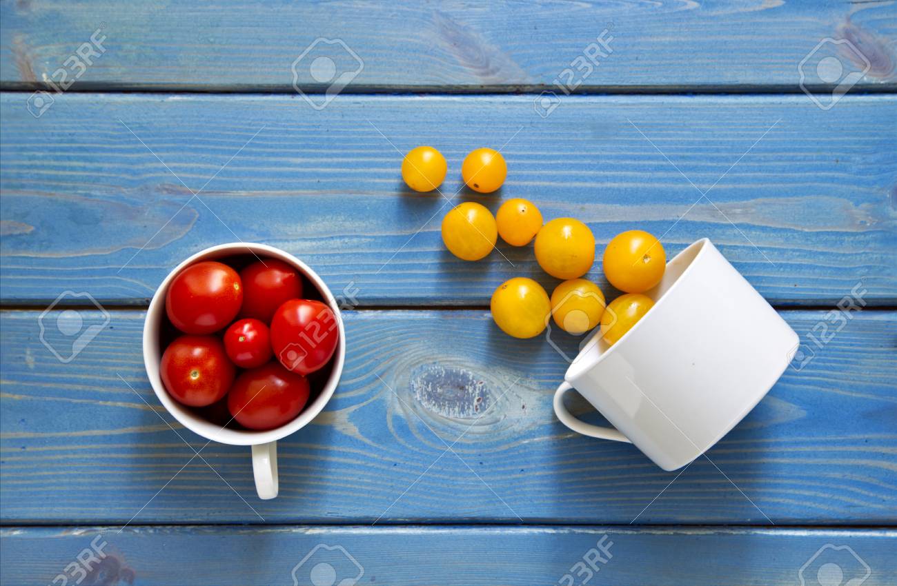 Download Two White Cups Pouring Red And Yellow Tomatoes Onto A Blue Wooden Stock Photo Picture And Royalty Free Image Image 65049775 Yellowimages Mockups