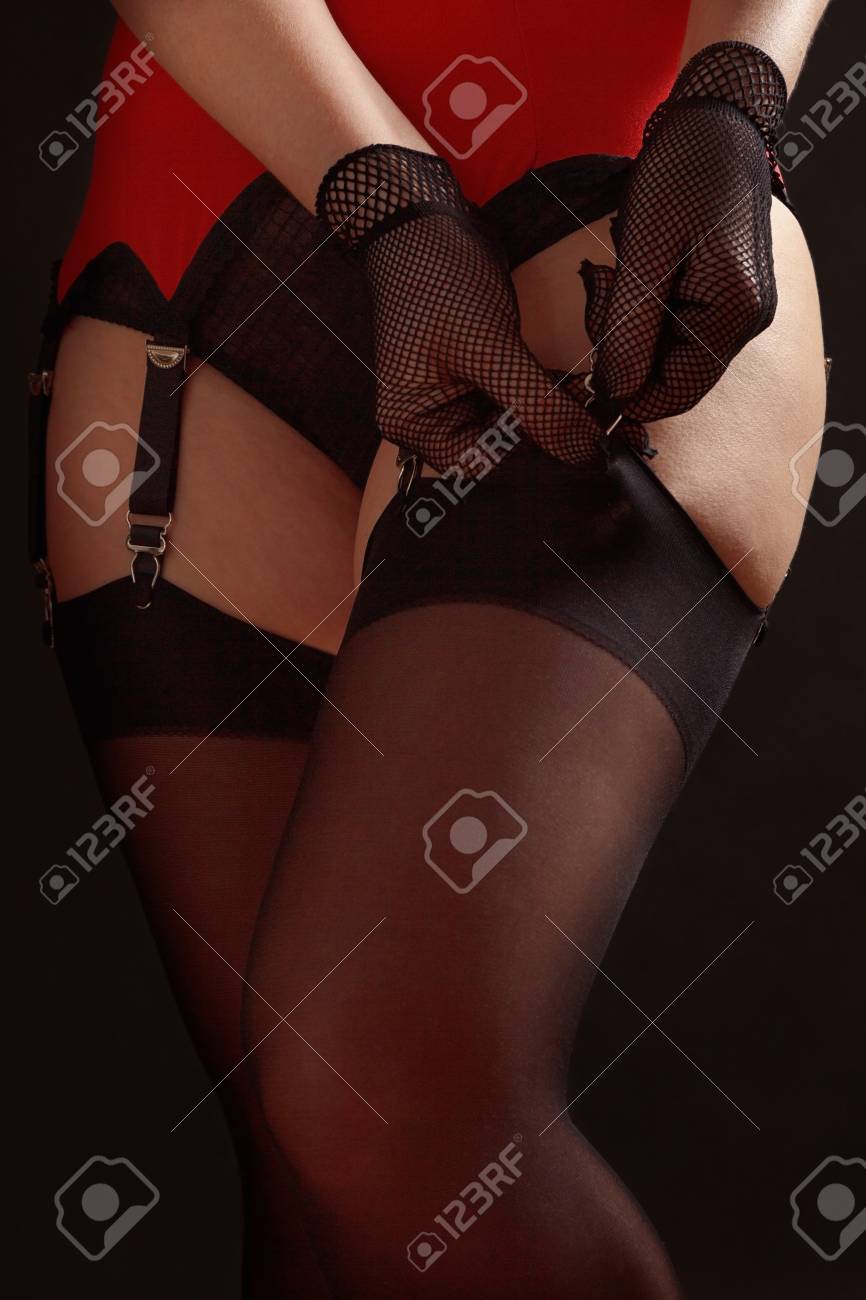 レトロ パンティストッキング エロ 女性は黒いストッキングを黒い背景のエロティックなガーターベルトに固定しますクローズアップの写真素材・画像素材 Image 120620176