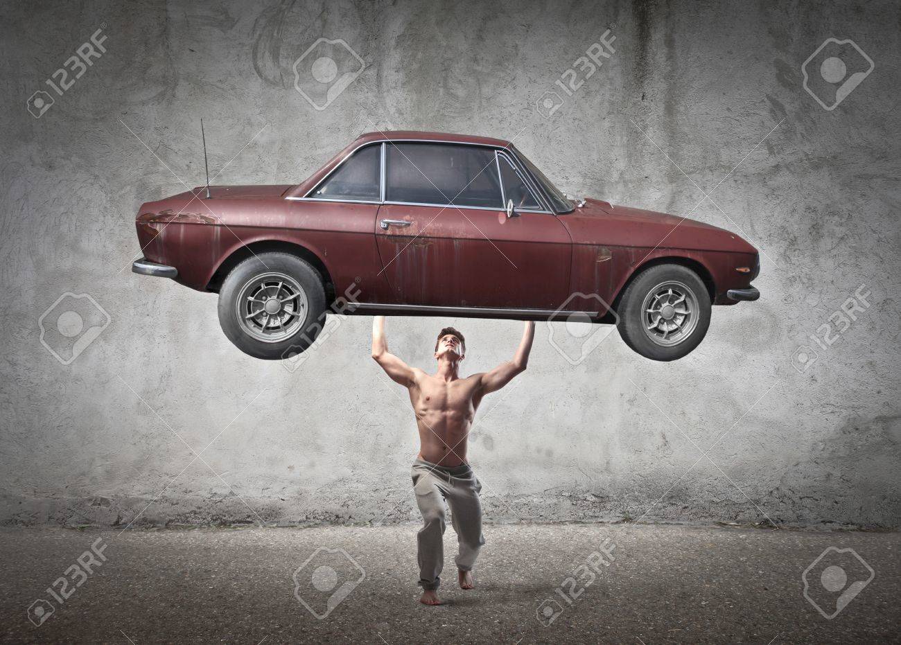 古い車を持ち上げる強い若い男性 の写真素材 画像素材 Image