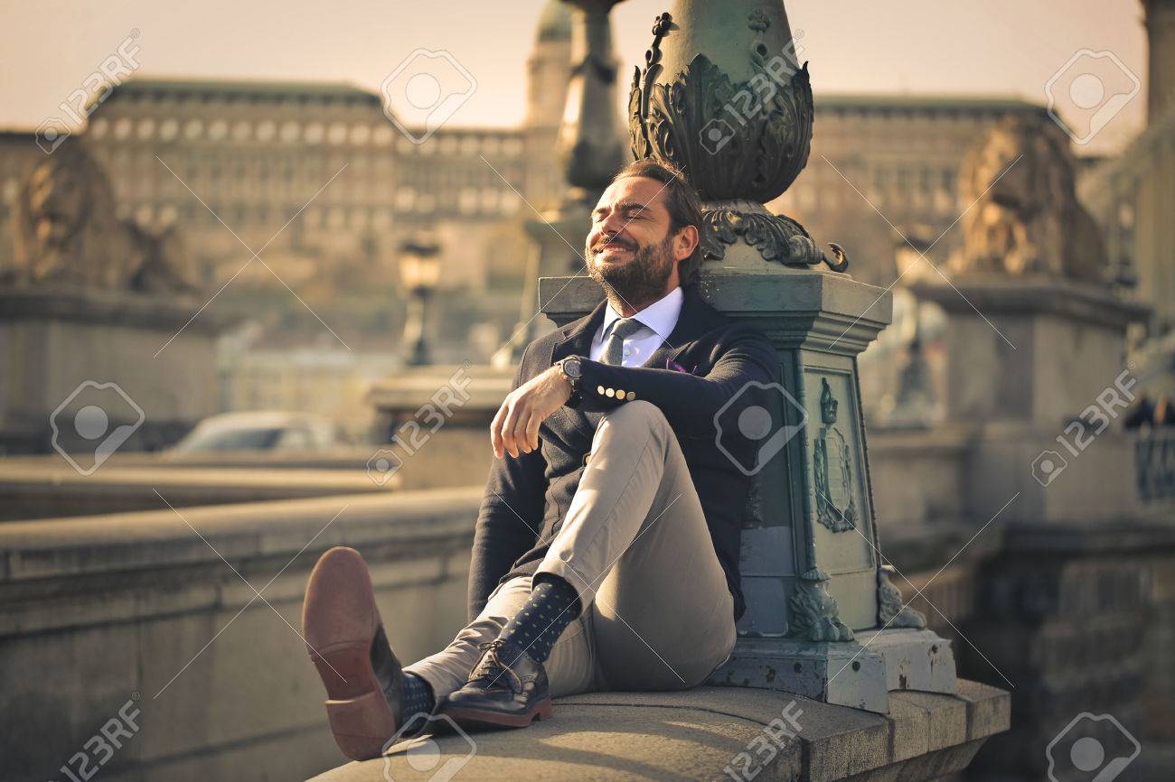Happy businessman sitting outdoors - 50742211 Happy businessman sitting outdoors - 50742211