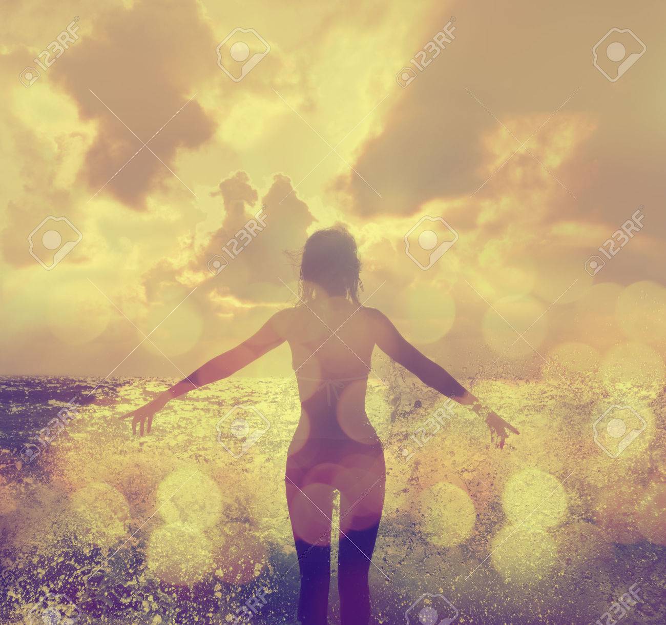 Beautiful Woman in Bikini Standing in the Sea Waves and Enjoying Sunshine with Open Arms - 27413455 Beautiful Woman in Bikini Standing in the Sea Waves and Enjoying Sunshine with Open Arms - 27413455