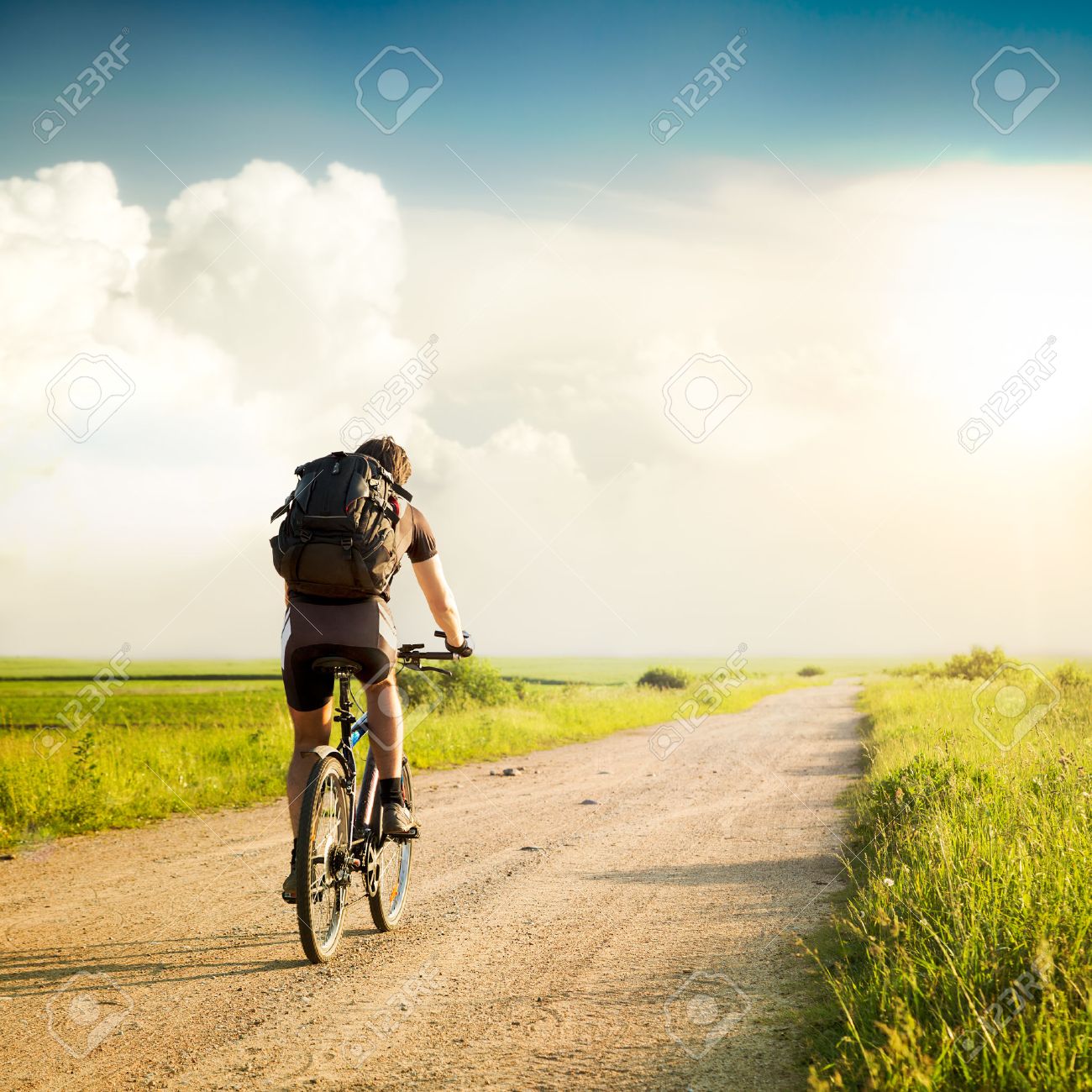 Rear View of a Man with Backpack Riding a Bicycle on Beautiful Nature Background. Healthy Lifestyle and Travel Concept. Styled Toned Photo. Copyspace. - 33651787 Rear View of a Man with Backpack Riding a Bicycle on Beautiful Nature Background. Healthy Lifestyle and Travel Concept. Styled Toned Photo. Copyspace. - 33651787