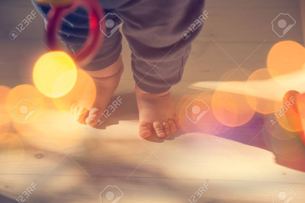 Small Baby Feet on Wooden Floor. First Steps Concept. Shallow Depth of Field. Toned Photo with Bokeh and Copy Space. - 47917490 Small Baby Feet on Wooden Floor. First Steps Concept. Shallow Depth of Field. Toned Photo with Bokeh and Copy Space. - 47917490
