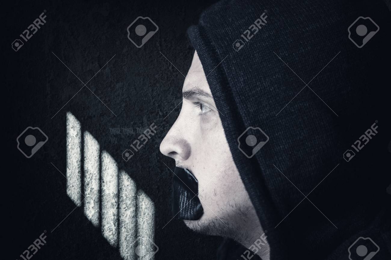 パーカーに黒テープで覆われて口と男性囚人禁止彼不潔な刑務所の独房の前に無料の Speeching の写真素材 画像素材 Image