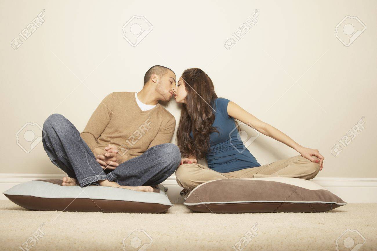 Young Hispanic Couple Sitting On Floor Pillows Kissing San Rafael