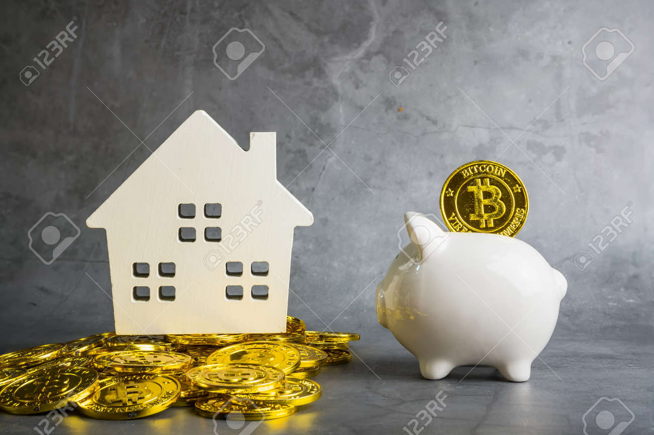 テーブルの上の貯金箱と木製の家のモデル、ビジネスと金融の概念を持つビットコインのお金。お金の概念を節約します。デジタル時代のビットコインファイナンスの写真素材・画像素材  Image 168687241
