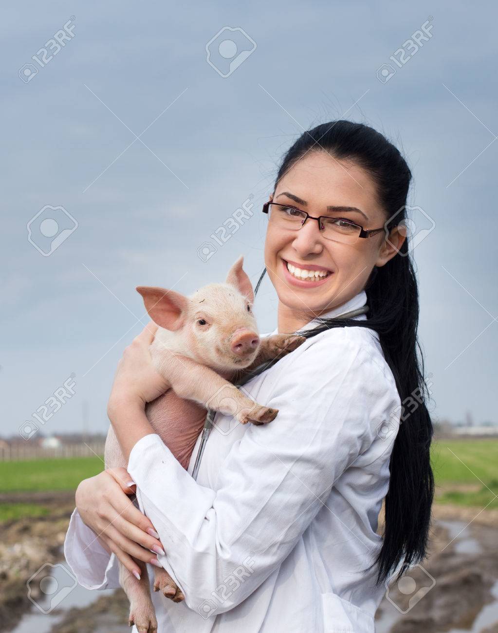 Happy young veterinarian girl holding cute piglet in her arms on the farm - 53744914 Happy young veterinarian girl holding cute piglet in her arms on the farm - 53744914
