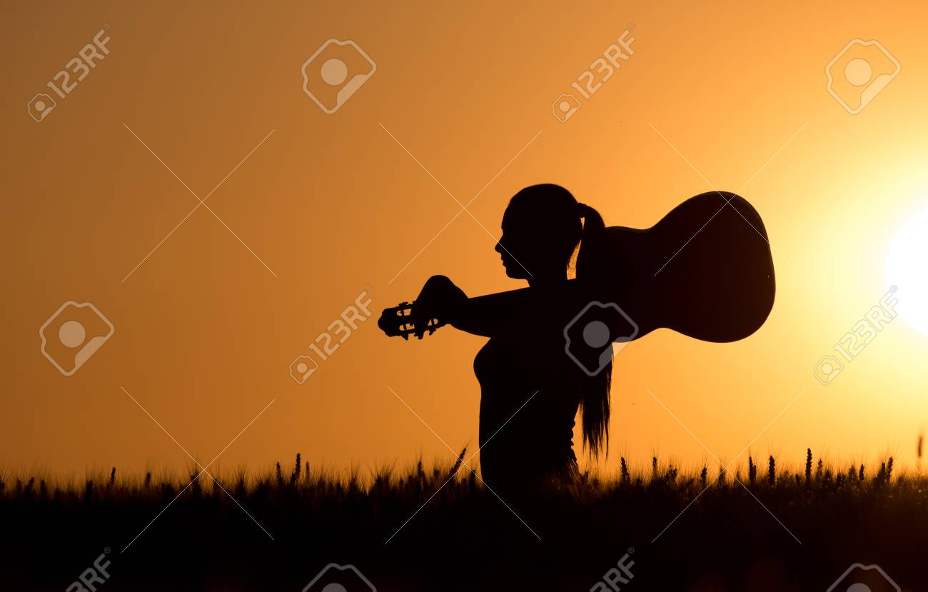 Silhouette Of Young Woman With Guitar On Shoulder Walking Through Wheat  Field At Sunset In Summertime Stock Photo, Picture and Royalty Free Image.  Image 57946204., image size:1300x829