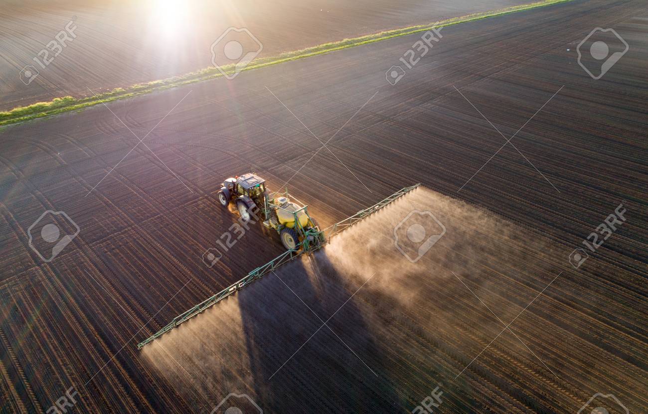 Aerial image of tractor spraying soil and young crop in springtime in field - 101101809 Aerial image of tractor spraying soil and young crop in springtime in field - 101101809
