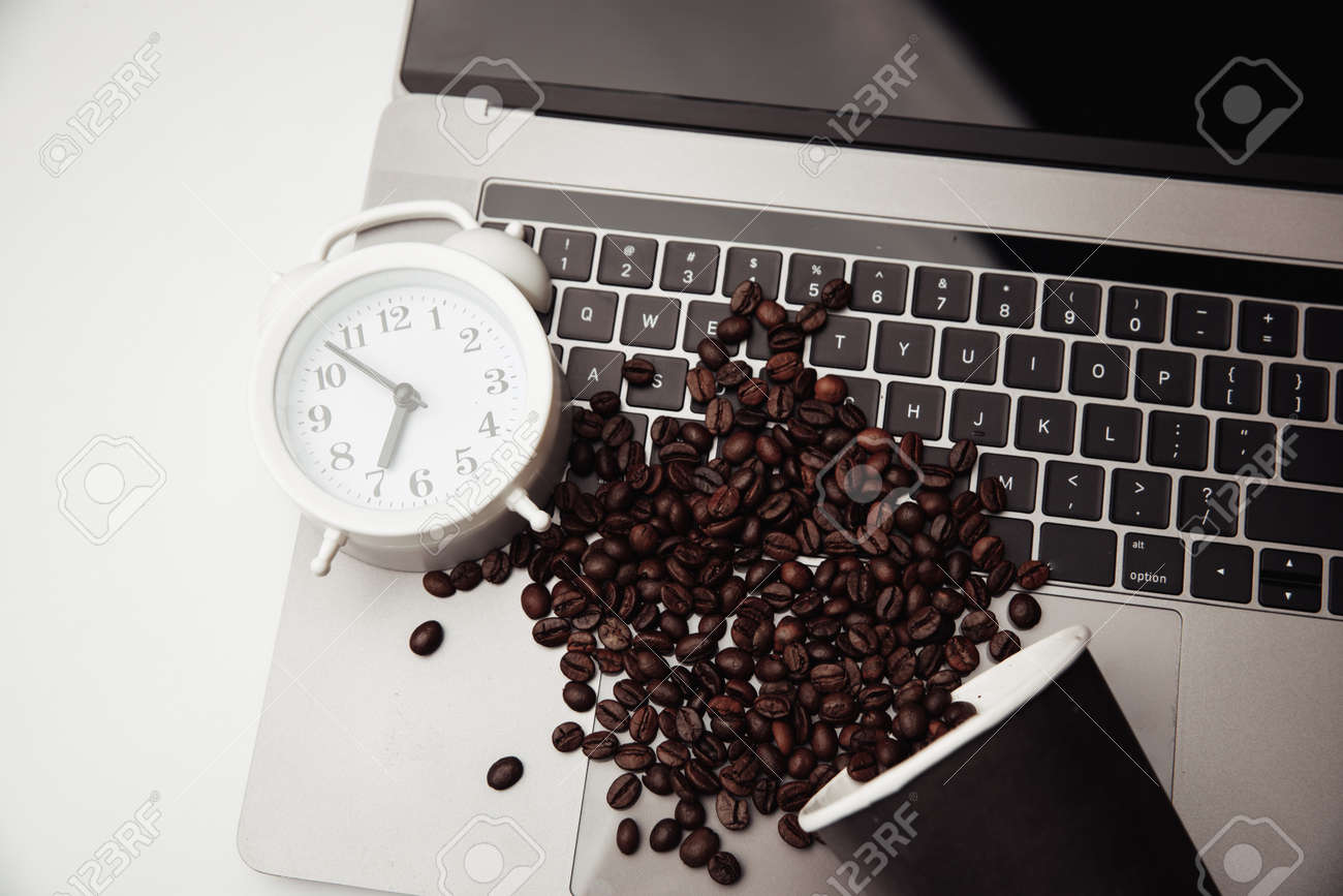 A cup of coffee on keyboard, alarm clock and coffee beans. Top view - 169819536 A cup of coffee on keyboard, alarm clock and coffee beans. Top view - 169819536