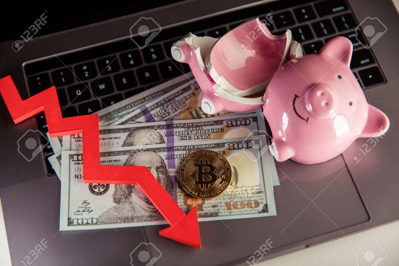 Bitcoin, broken piggy bnak and arrow down close-up. Cryptocurrency and investment concept. - 169819671 Bitcoin, broken piggy bnak and arrow down close-up. Cryptocurrency and investment concept. - 169819671