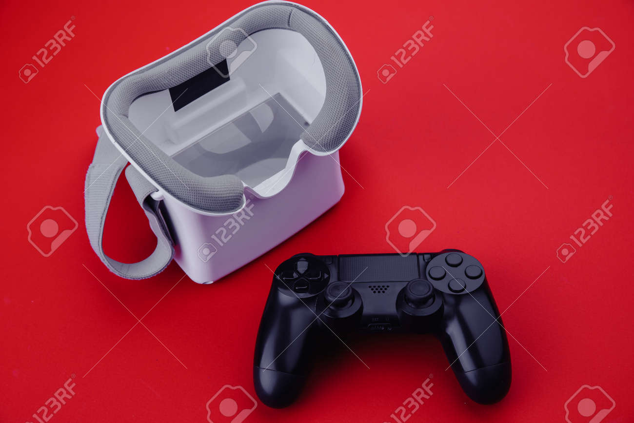 Gaming concept. VR virtual reality glasses with gamepad on red background - 169819669 Gaming concept. VR virtual reality glasses with gamepad on red background - 169819669