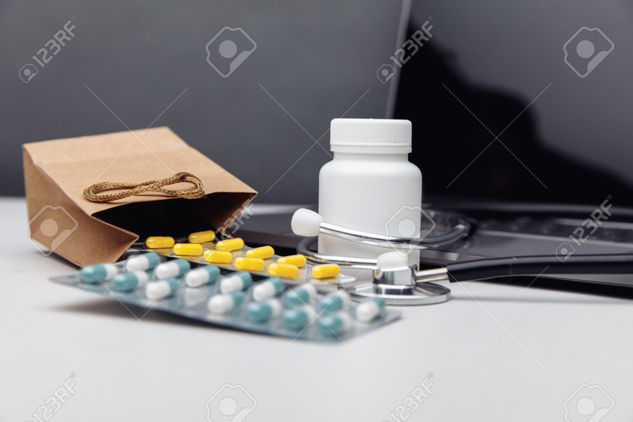 Online pharmacy shopping concept. Laptop and paper bags filled with assorted prescription medicines - 169820263 Online pharmacy shopping concept. Laptop and paper bags filled with assorted prescription medicines - 169820263