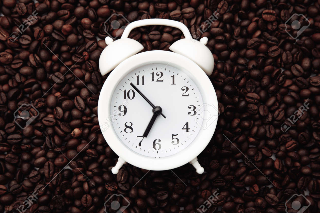 Alarm clock on coffee bean background. Morning with cup of coffee - 169820853 Alarm clock on coffee bean background. Morning with cup of coffee - 169820853