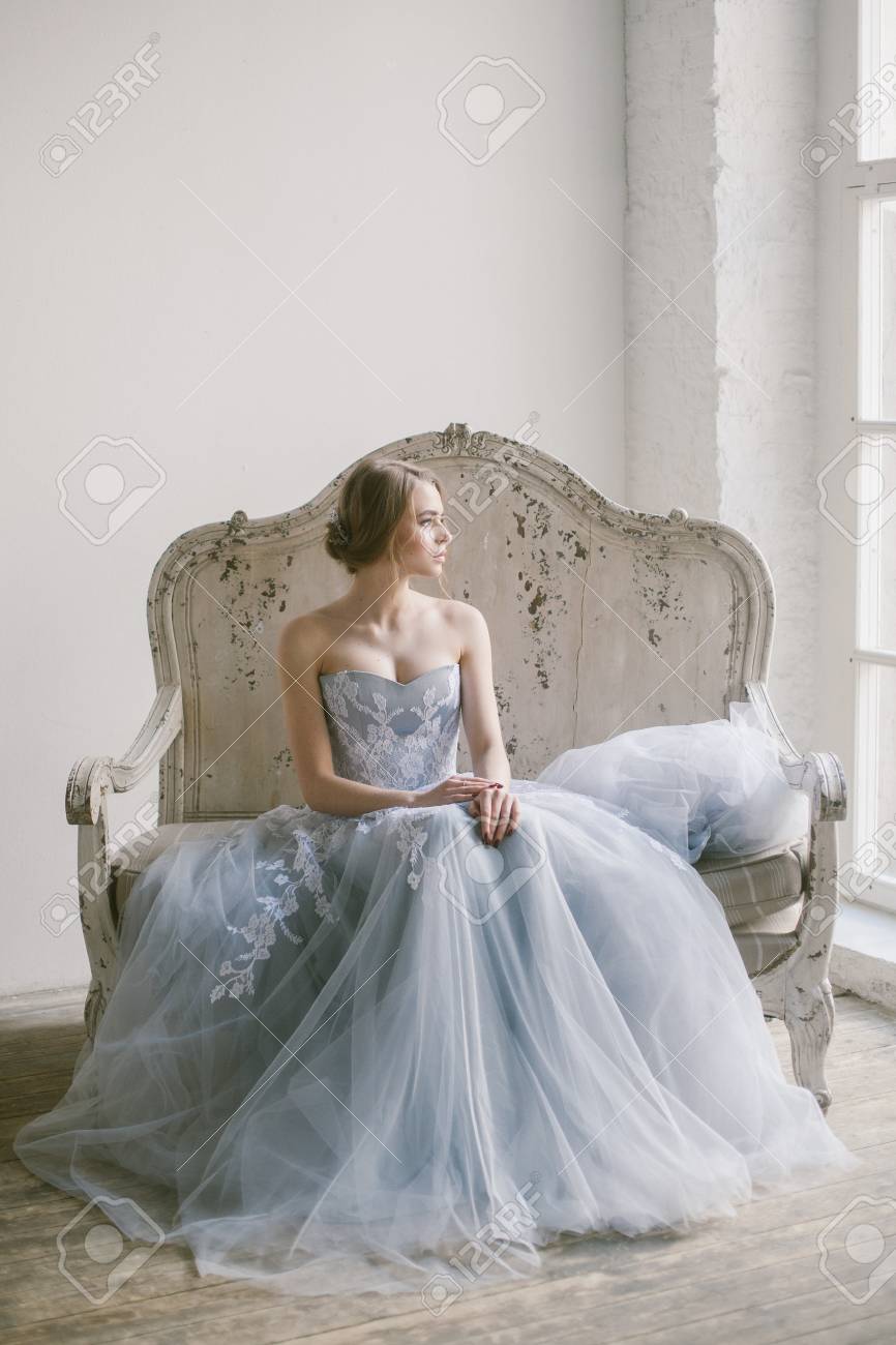 ソファに座ってグレーのレースのドレスを着た若い美しい現代の花嫁の肖像画 の写真素材 画像素材 Image