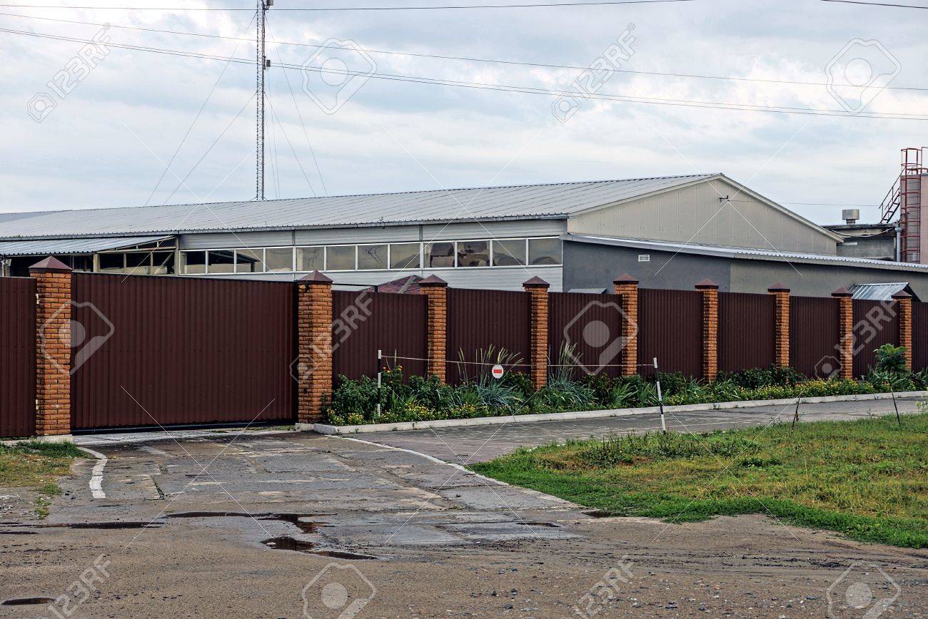 茶色のフェンスと道路の近く産業倉庫の前で鉄の門 の写真素材 画像素材 Image