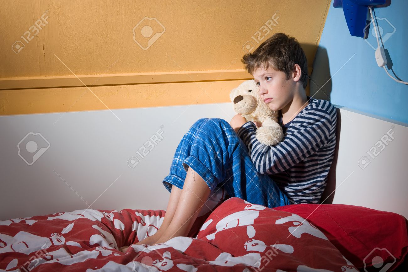 A Young Boy Is Sitting Afraid And Depressed On His Bed In His.. Stock Photo, Picture And Royalty Free Image. Image 23422433.