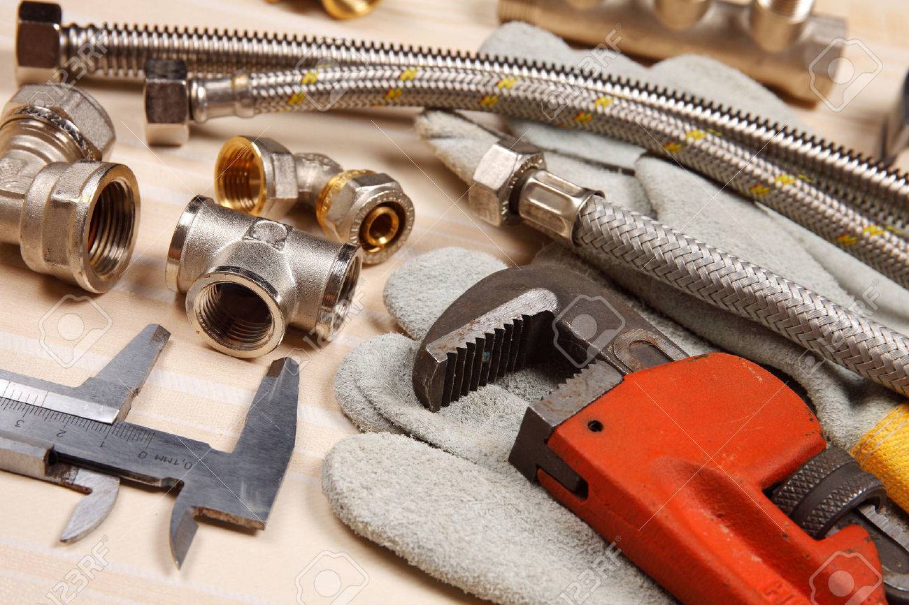 Set of plumbing and tools on the table. Fitting, suede gloves and adjustable wrench for plumbing works - 55246352 Set of plumbing and tools on the table. Fitting, suede gloves and adjustable wrench for plumbing works - 55246352