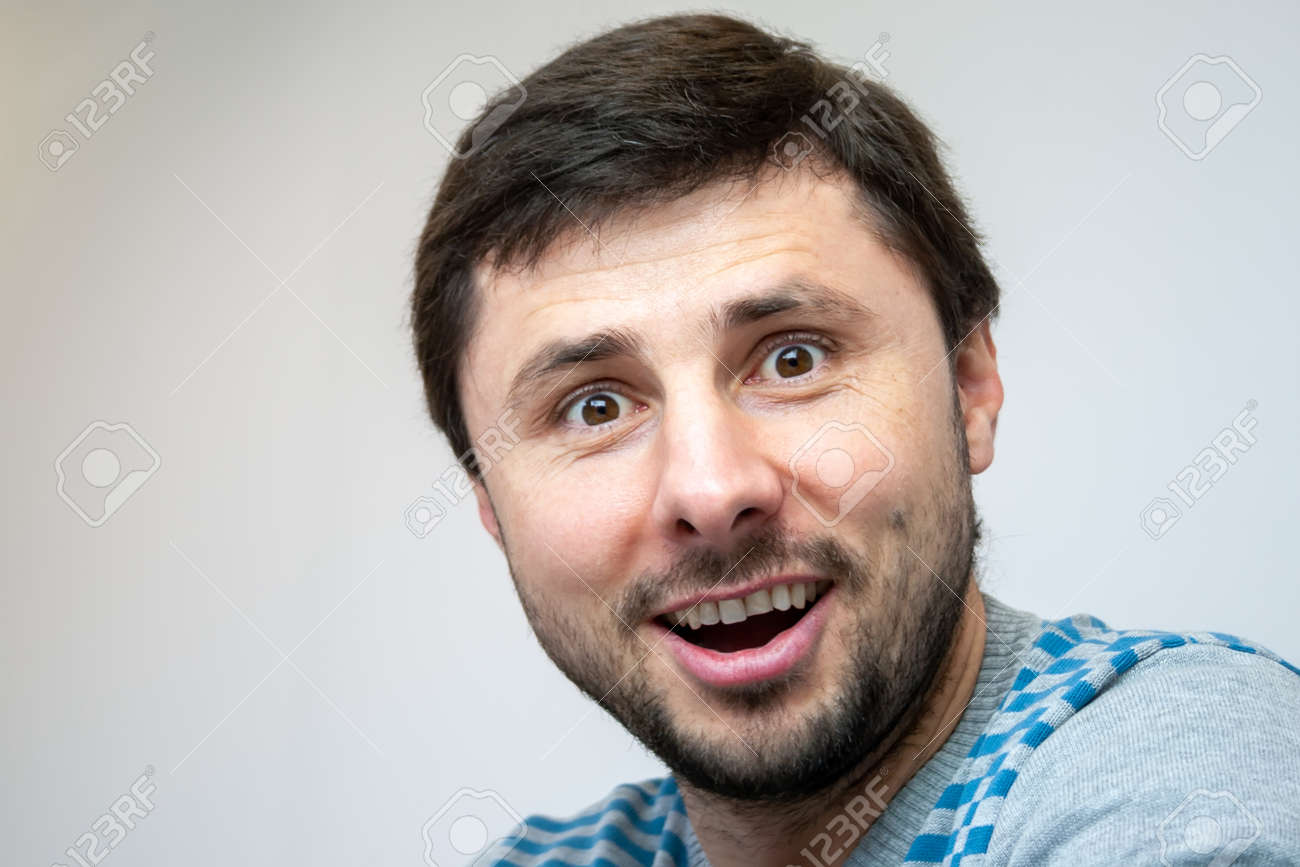 Overjoyed smiling handsome bearded man looks surprised in camera - 156753156 Overjoyed smiling handsome bearded man looks surprised in camera - 156753156