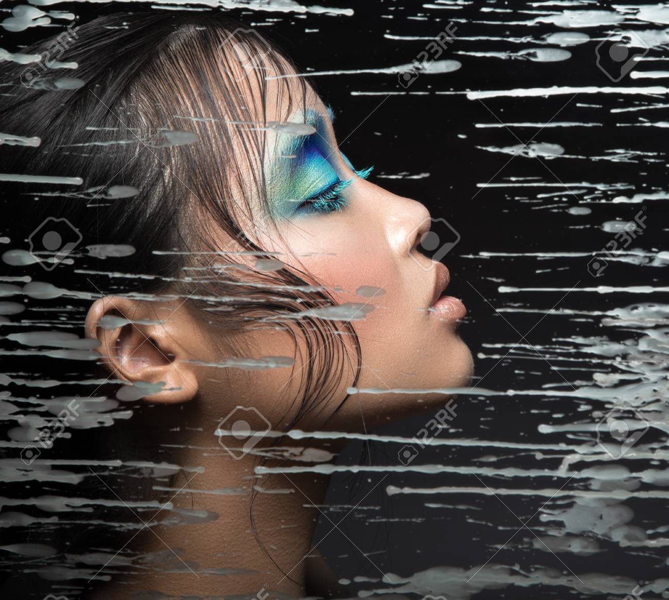 Beautiful Asian Girl With Bright Blue Make Up Behind Glass With