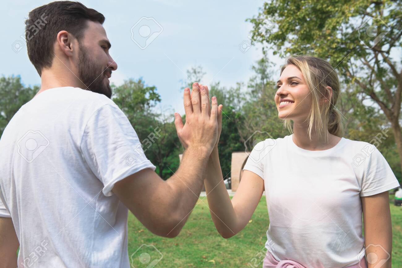 Young couple smile and greet with hi-five when first meet in the garden - 148566985 Young couple smile and greet with hi-five when first meet in the garden - 148566985