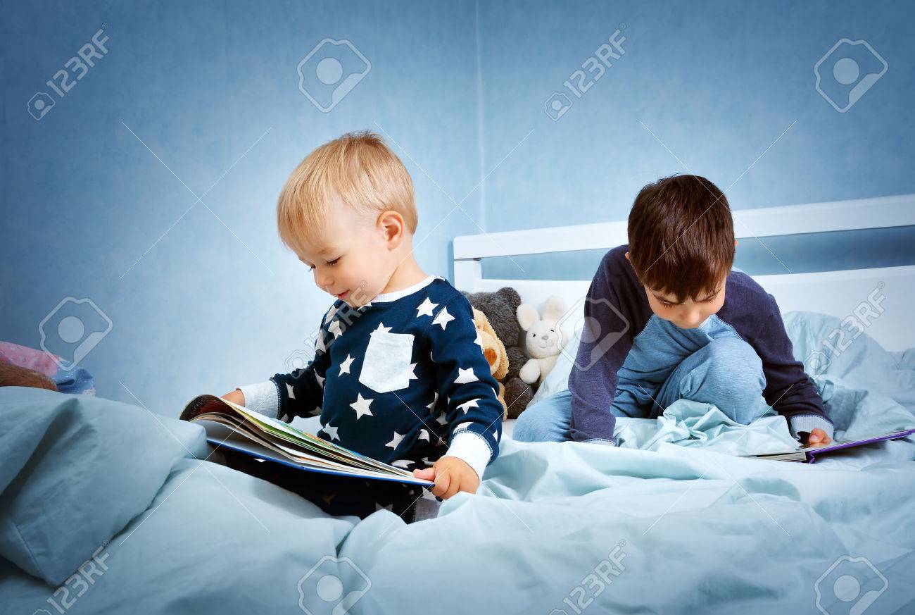 Brothers sitting in the bed in pyjamas and reading books - 63246250 Brothers sitting in the bed in pyjamas and reading books - 63246250