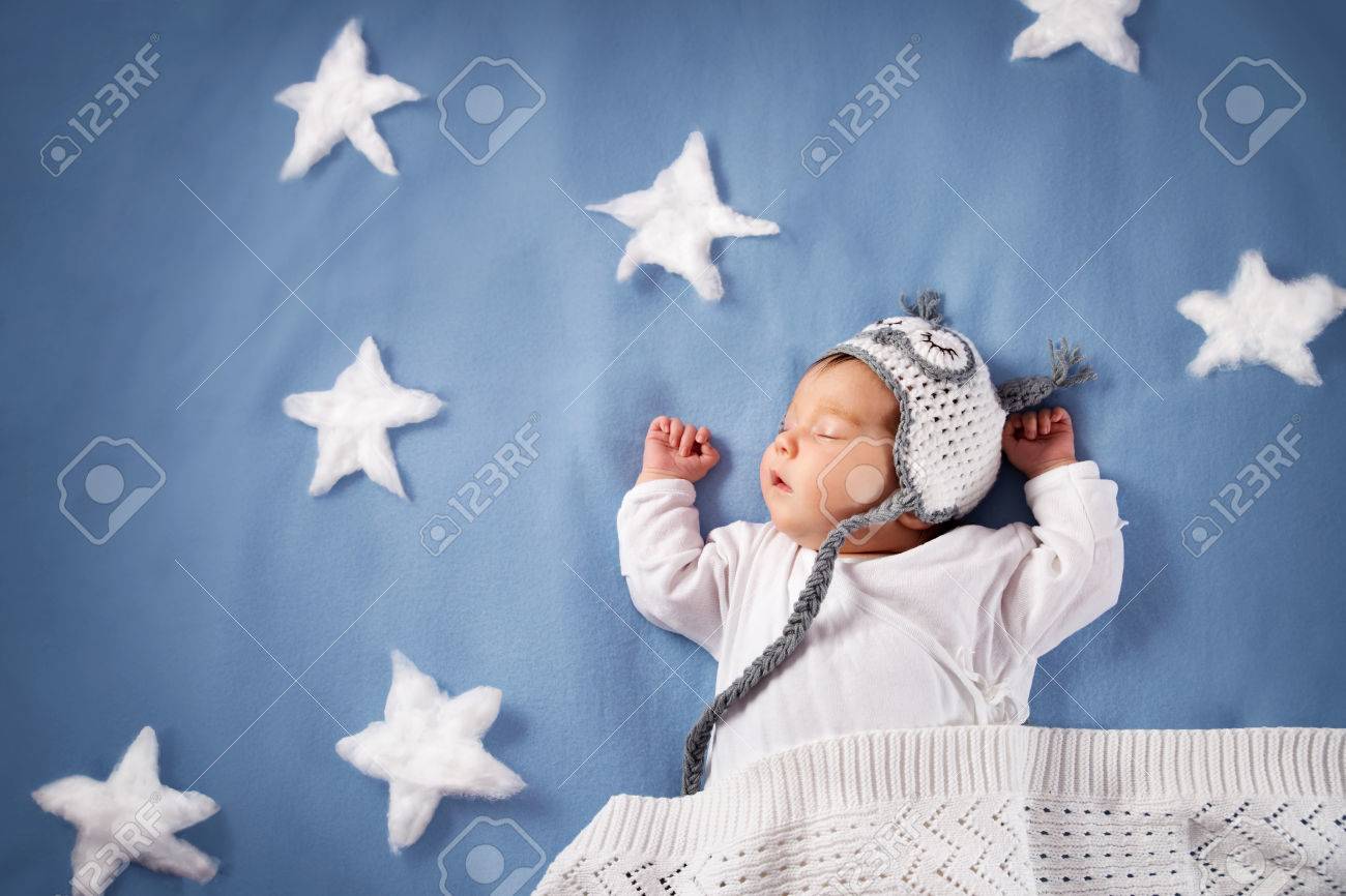 Cute newborn baby girl lying in the bed. 2 month old child in owl hat sleeping on blue blanket - 76556170 Cute newborn baby girl lying in the bed. 2 month old child in owl hat sleeping on blue blanket - 76556170