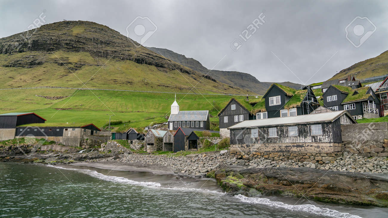 Bour, Faroe Islands - August 2019: Typical nordic village overlooking a fjord surrounded by green mountains . - 164356076 Bour, Faroe Islands - August 2019: Typical nordic village overlooking a fjord surrounded by green mountains . - 164356076