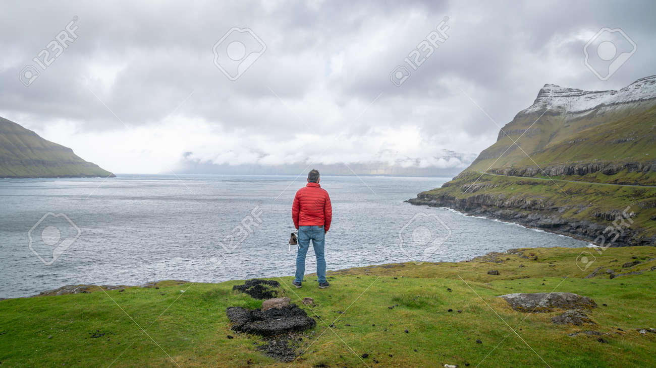 Torshavn, Faroe Islands - August 2019: Unidentified man looking at the dramatic landscape in Faroe Islands, Denmark - 164356039 Torshavn, Faroe Islands - August 2019: Unidentified man looking at the dramatic landscape in Faroe Islands, Denmark - 164356039