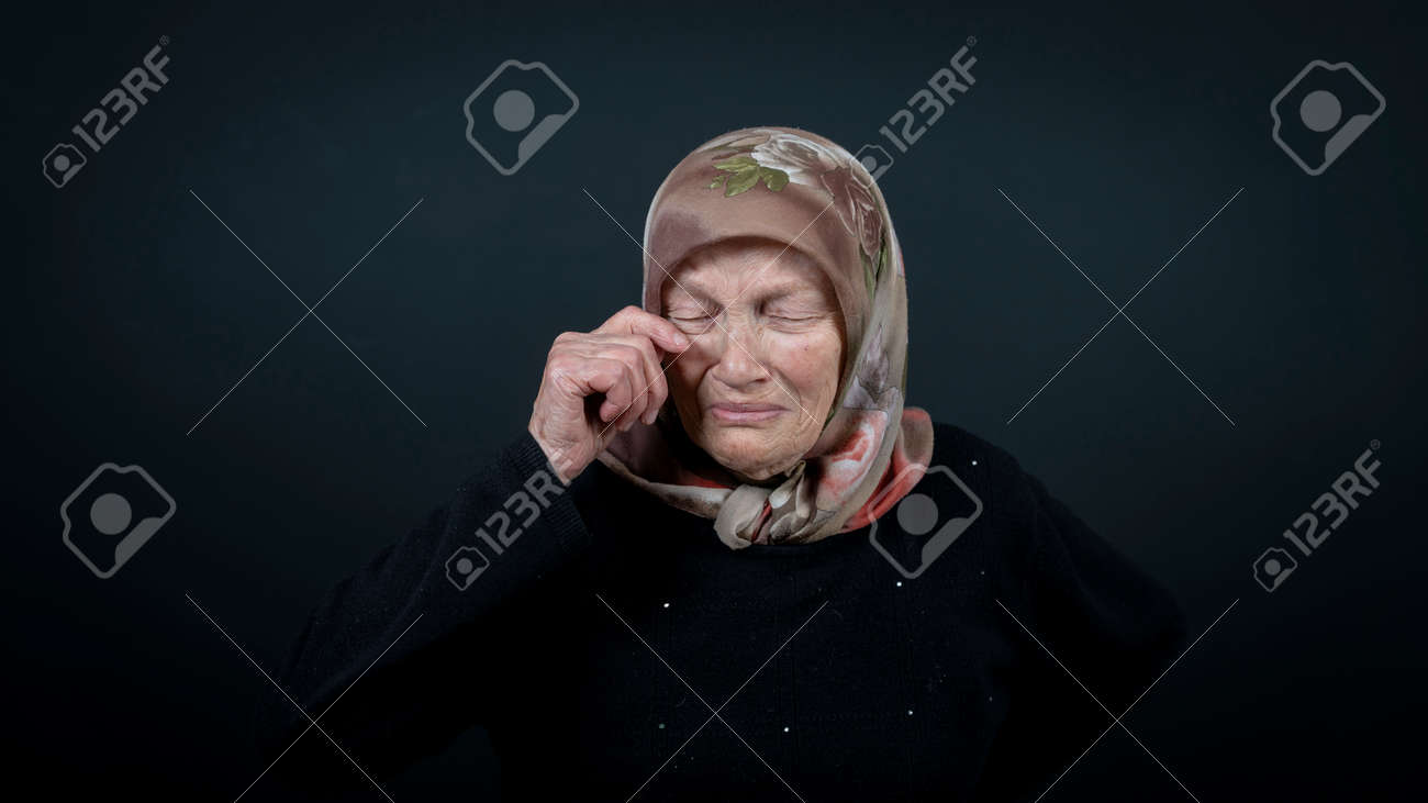 Portrait of a Turkish senior muslim woman with black background. She is sad, unhappy and crying. - 172150645 Portrait of a Turkish senior muslim woman with black background. She is sad, unhappy and crying. - 172150645